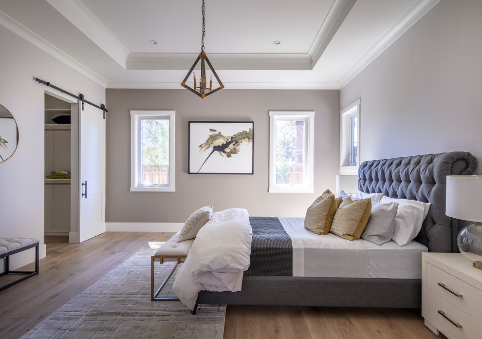 Large country master bedroom in San Francisco with grey walls, light hardwood floors and grey floor.