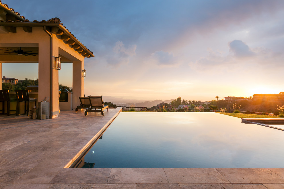 Inspiration for a large mediterranean backyard rectangular infinity pool in Los Angeles with a hot tub and tile.