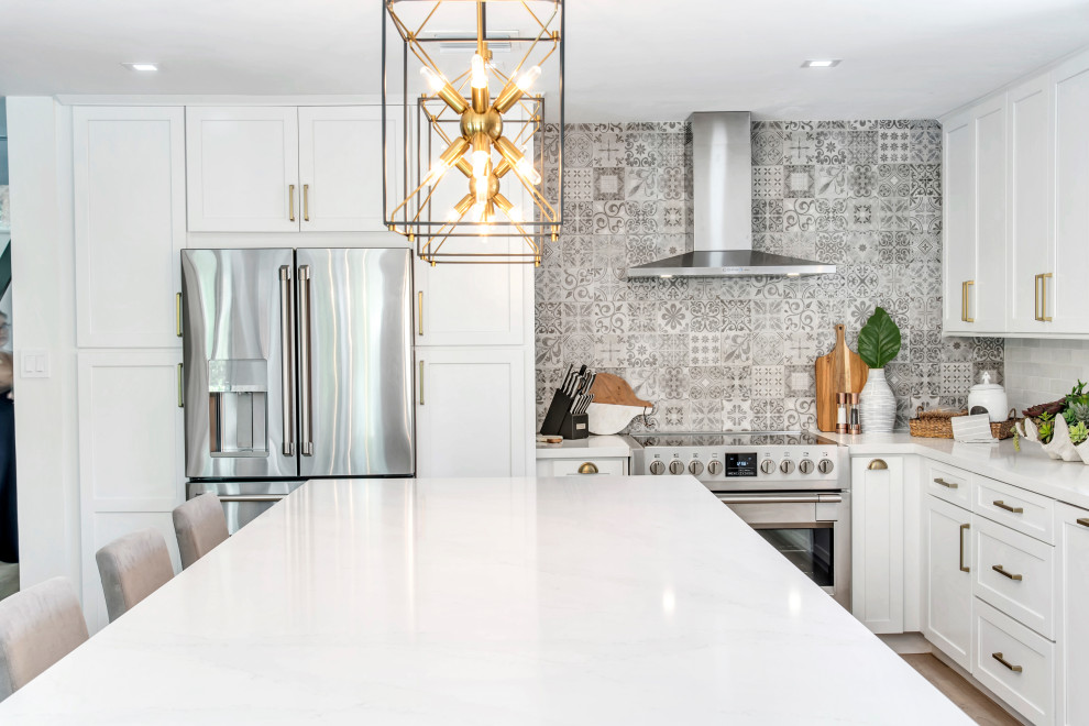 Example of a mid-sized transitional l-shaped open concept kitchen design in Miami with shaker cabinets, white cabinets, quartz countertops, gray backsplash, porcelain backsplash, stainless steel appliances, an island and white countertops