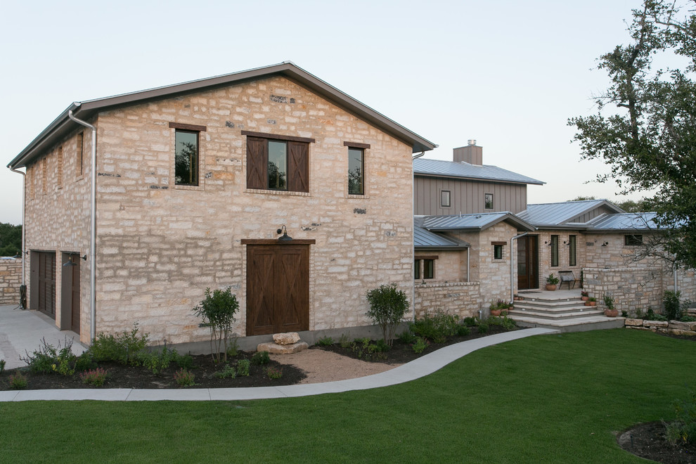 Large country two-storey grey house exterior in Austin with stone veneer, a gable roof and a metal roof.