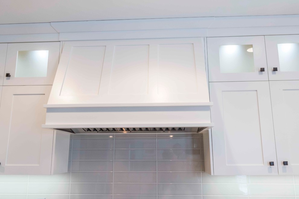 Mid-sized transitional u-shaped medium tone wood floor and brown floor home design photo in Calgary with an undermount sink, flat-panel cabinets, white cabinets, marble countertops, gray backsplash, ceramic backsplash, paneled appliances and an island