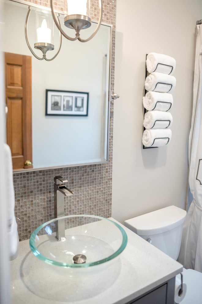 This is an example of a small modern master bathroom in New Orleans with furniture-like cabinets, grey cabinets, an alcove tub, a shower/bathtub combo, a one-piece toilet, gray tile, ceramic tile, grey walls, ceramic floors, a vessel sink, engineered quartz benchtops, grey floor, an open shower and white benchtops.