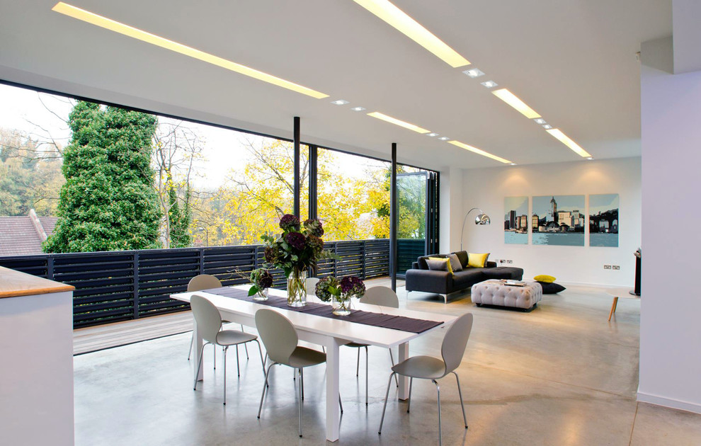 Contemporary open plan dining in London with white walls and concrete floors.