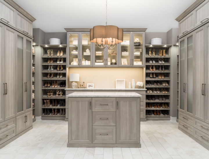 Inspiration for a large transitional gender-neutral dressing room in Charleston with glass-front cabinets, beige cabinets, porcelain floors and grey floor.