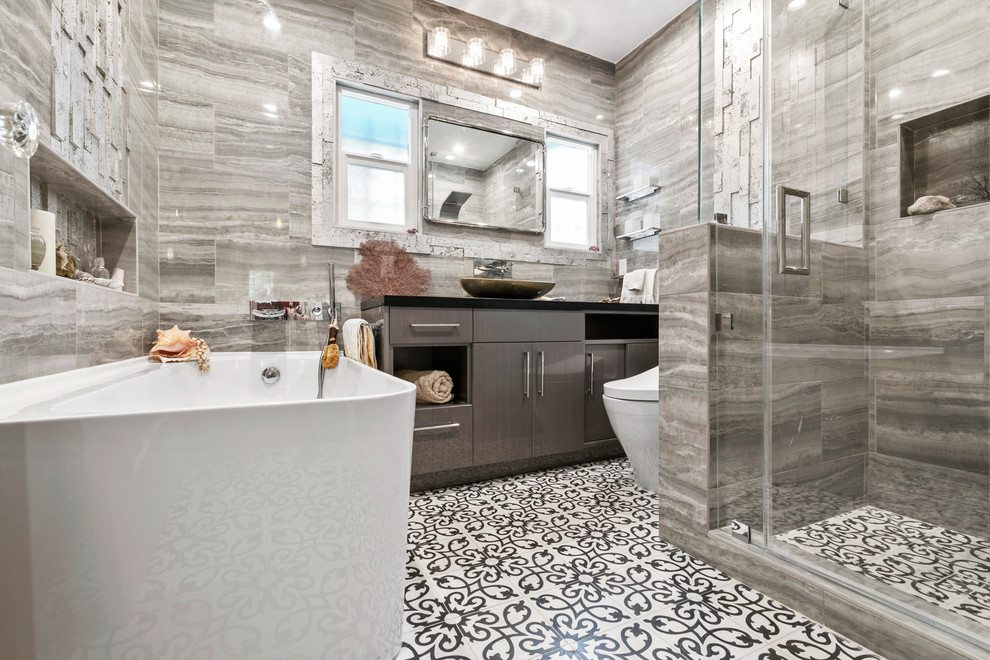 Inspiration for a small beach style master bathroom in Los Angeles with flat-panel cabinets, black cabinets, a corner tub, a corner shower, a bidet, gray tile, porcelain tile, grey walls, cement tiles, a vessel sink, engineered quartz benchtops, multi-coloured floor and black benchtops.