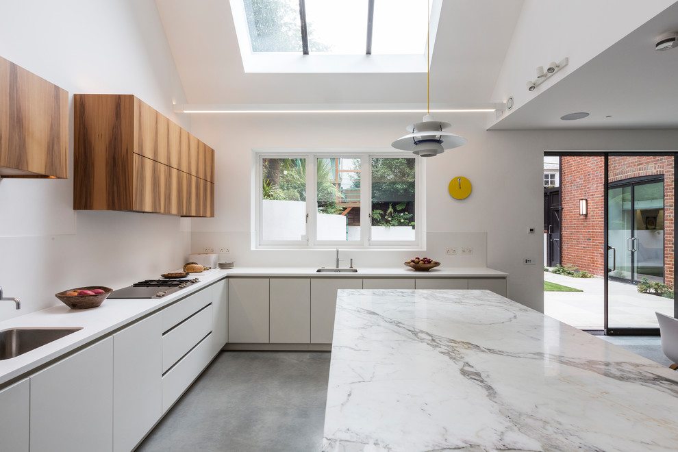 Inspiration for a large contemporary u-shaped open plan kitchen in London with a double-bowl sink, flat-panel cabinets, white cabinets, marble benchtops, white splashback, panelled appliances, cement tiles, with island, grey floor and white benchtop.
