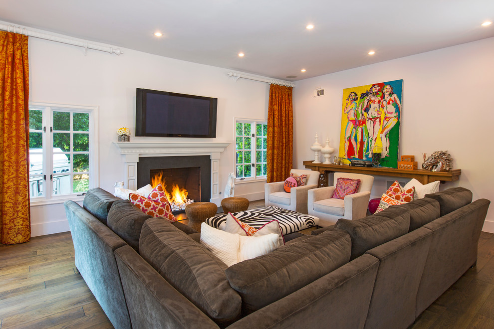 Mid-sized eclectic enclosed family room in Los Angeles with white walls, medium hardwood floors, a standard fireplace, a stone fireplace surround and a wall-mounted tv.