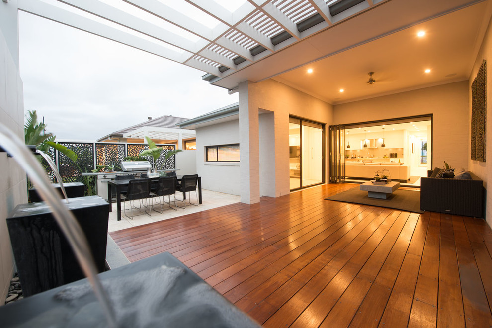 Inspiration for a large contemporary backyard deck in Sydney with a water feature and a roof extension.