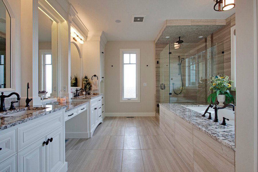 Photo of a large country master bathroom in Calgary with an undermount sink, raised-panel cabinets, white cabinets, granite benchtops, an undermount tub, gray tile, stone tile, grey walls and marble floors.