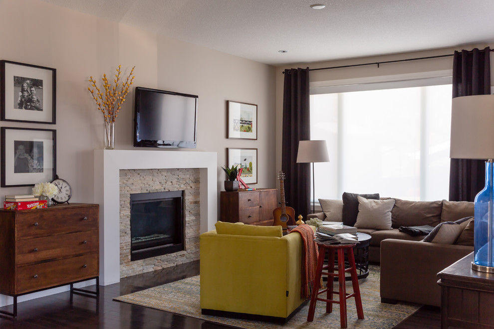 This is an example of a mid-sized contemporary formal enclosed living room in Edmonton with a standard fireplace, a wall-mounted tv, beige walls and carpet.