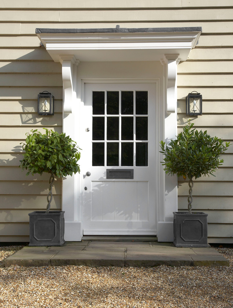 This is an example of a country front door in Wiltshire with a single front door, a white front door and beige walls.