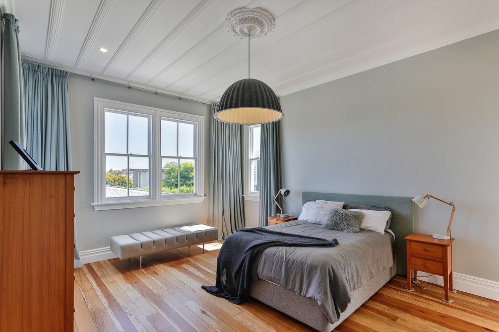 Large traditional master bedroom in Auckland with grey walls, medium hardwood floors and brown floor.