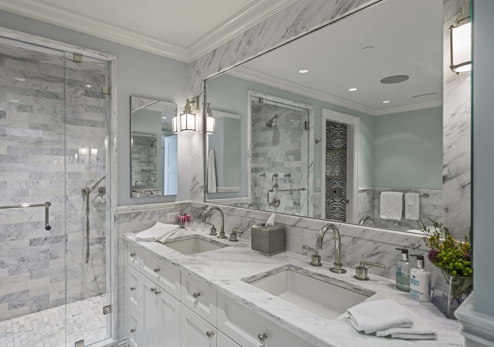 Large transitional master white tile and stone tile marble floor corner bathtub photo in Boston with an undermount sink, recessed-panel cabinets, white cabinets, marble countertops, a wall-mount toilet and blue walls