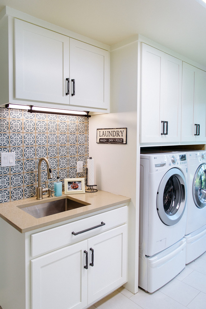 Photo of a transitional single-wall dedicated laundry room in Austin with an undermount sink, shaker cabinets, white cabinets, a side-by-side washer and dryer, white floor and beige benchtop.