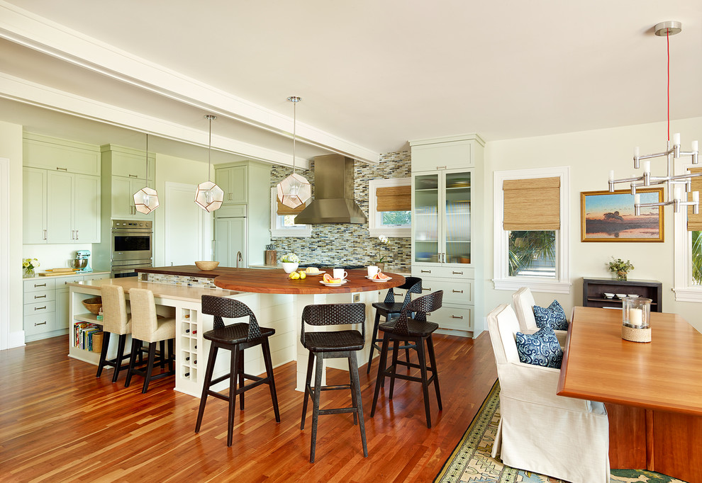 This is an example of a beach style eat-in kitchen in Charleston with shaker cabinets, green cabinets, medium hardwood floors, with island, stainless steel appliances, multi-coloured splashback, mosaic tile splashback and brown benchtop.