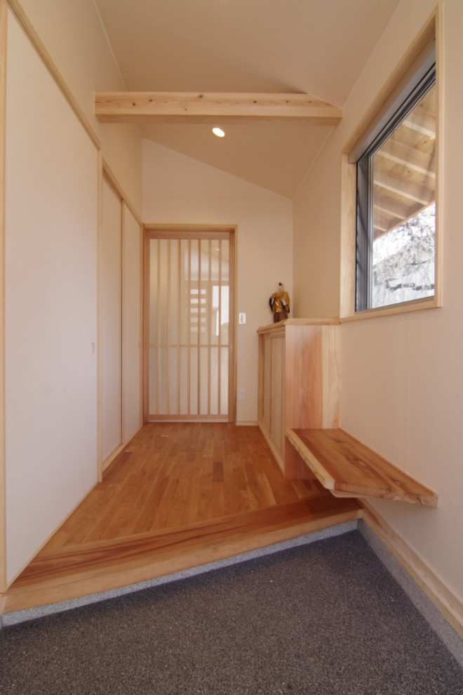 This is an example of an entry hall in Tokyo Suburbs with medium hardwood floors, a sliding front door and exposed beam.
