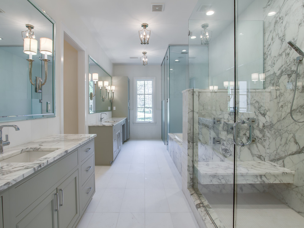 Photo of a large transitional master bathroom in Other with beaded inset cabinets, grey cabinets, a drop-in tub, a double shower, a one-piece toilet, white tile, stone slab, grey walls, marble floors, an undermount sink and marble benchtops.