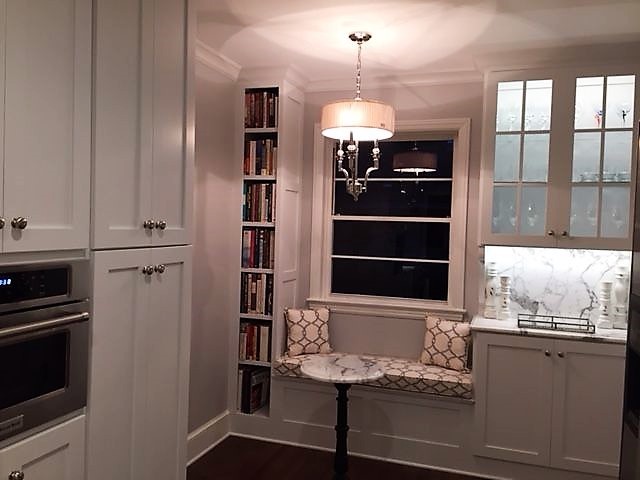 Inspiration for a mid-sized transitional galley medium tone wood floor and brown floor enclosed kitchen remodel with a farmhouse sink, shaker cabinets, white cabinets, marble countertops, white backsplash, marble backsplash, stainless steel appliances and no island