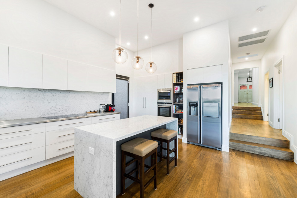 This is an example of a mid-sized contemporary l-shaped eat-in kitchen in Melbourne with an integrated sink, grey splashback, stainless steel appliances, medium hardwood floors and with island.