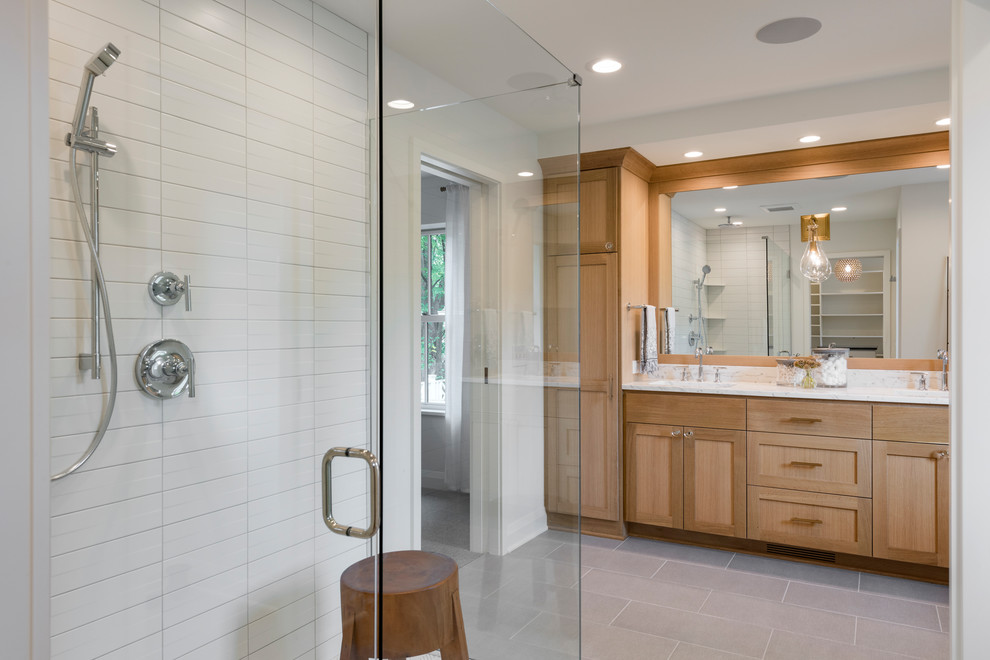 Design ideas for a mid-sized transitional master bathroom in Minneapolis with shaker cabinets, light wood cabinets, a corner shower, white walls, ceramic floors, an undermount sink, marble benchtops, grey floor, a hinged shower door and white benchtops.
