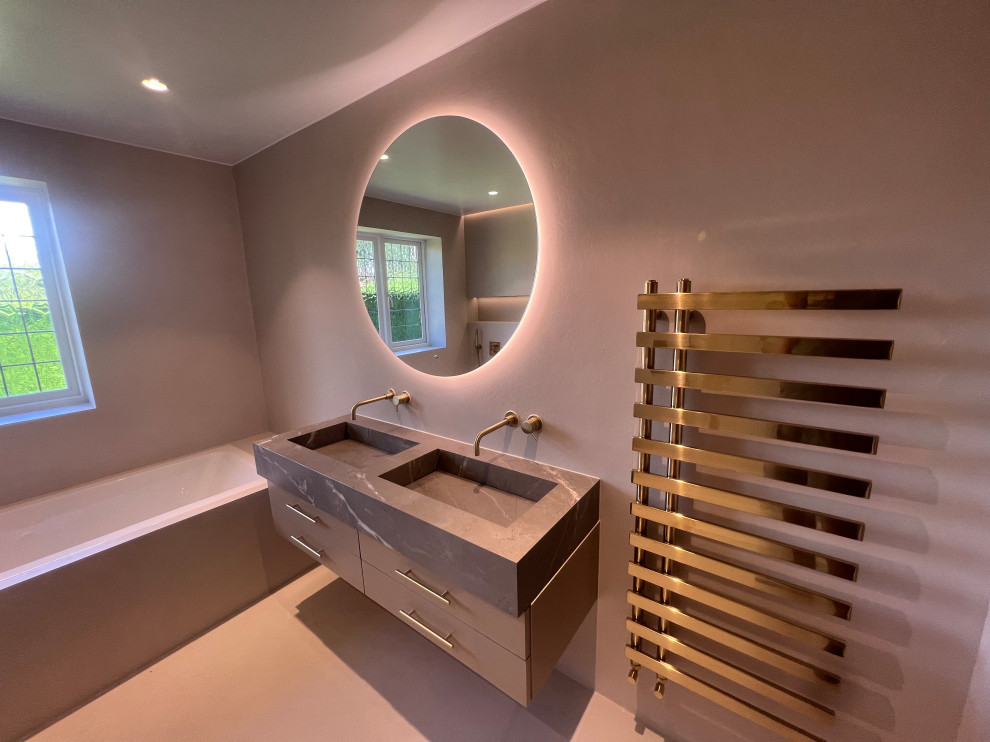 Small kids wet room bathroom in Hertfordshire with grey cabinets, a drop-in tub, a wall-mount toilet, grey walls, concrete floors, tile benchtops, an open shower, a double vanity and a floating vanity.