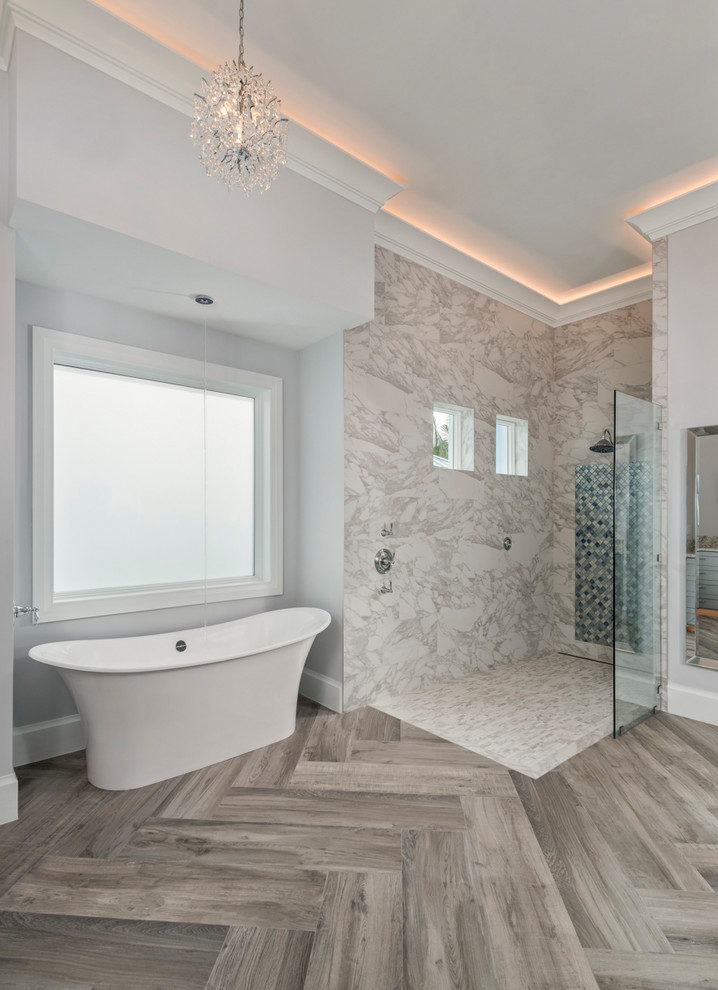 This is an example of a large transitional master bathroom in Miami with a freestanding tub, an open shower, a two-piece toilet, brown tile, porcelain tile, medium hardwood floors, an undermount sink, granite benchtops, shaker cabinets, grey cabinets and grey walls.
