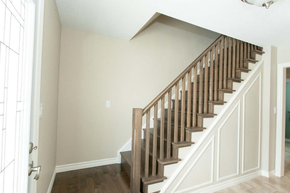 Example of a mid-sized transitional dark wood floor staircase design in Toronto with beige walls and a white front door