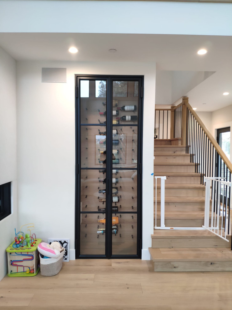 Inspiration for a small contemporary wine cellar in San Diego with light hardwood floors, storage racks and beige floor.