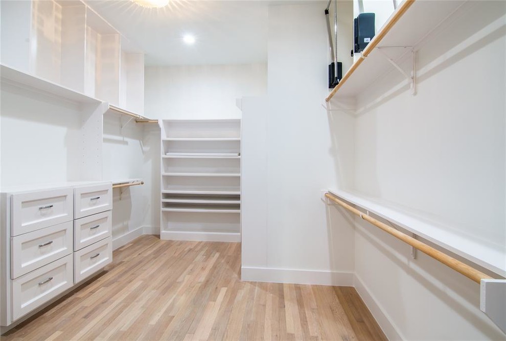 Inspiration for a large contemporary gender-neutral walk-in wardrobe in Houston with shaker cabinets, white cabinets, light hardwood floors and beige floor.