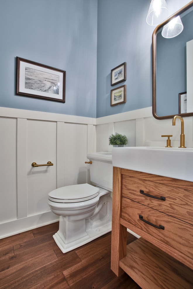 Foto på ett mellanstort maritimt toalett, med luckor med infälld panel, skåp i mellenmörkt trä, en toalettstol med separat cisternkåpa, blå väggar och mellanmörkt trägolv