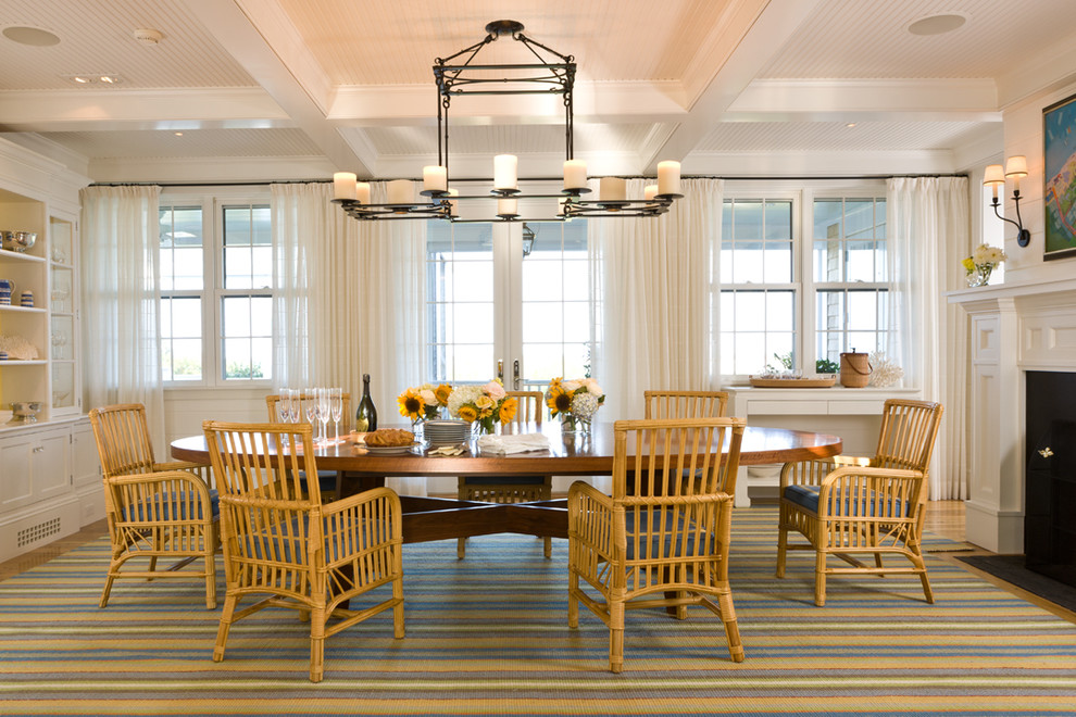 This is an example of a beach style separate dining room in Boston with white walls and a standard fireplace.