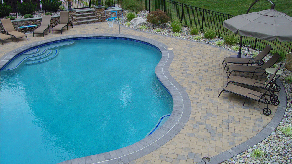 Example of a mid-sized backyard concrete paver and custom-shaped pool design in Baltimore