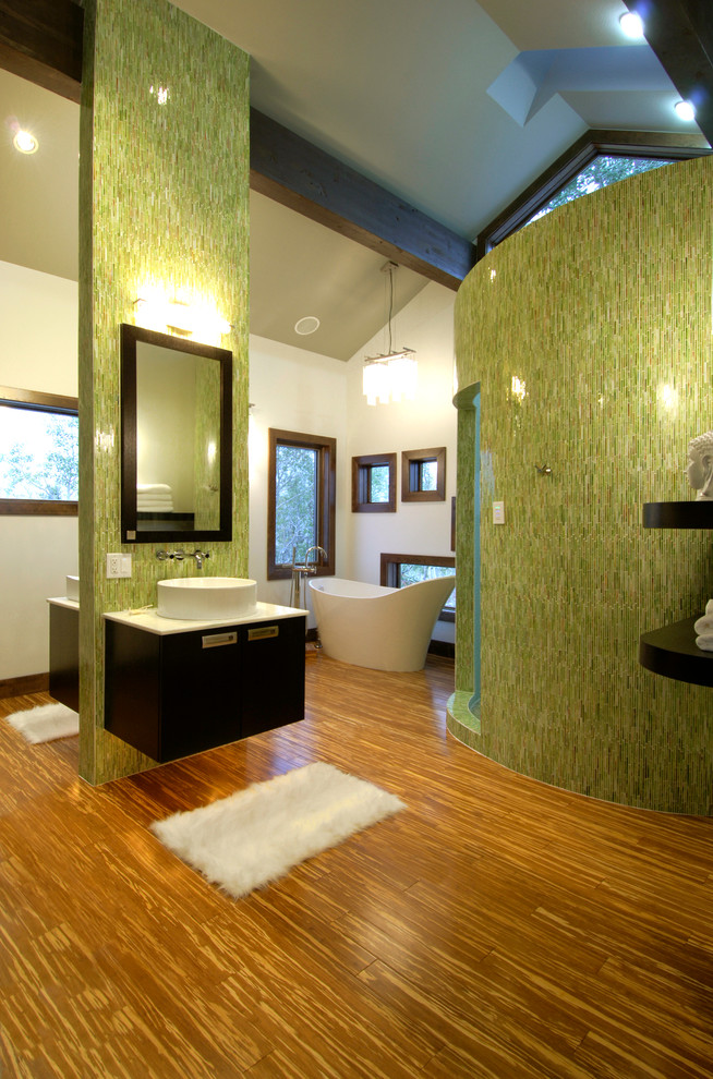This is an example of a contemporary bathroom in Denver with a vessel sink, a freestanding tub and green walls.