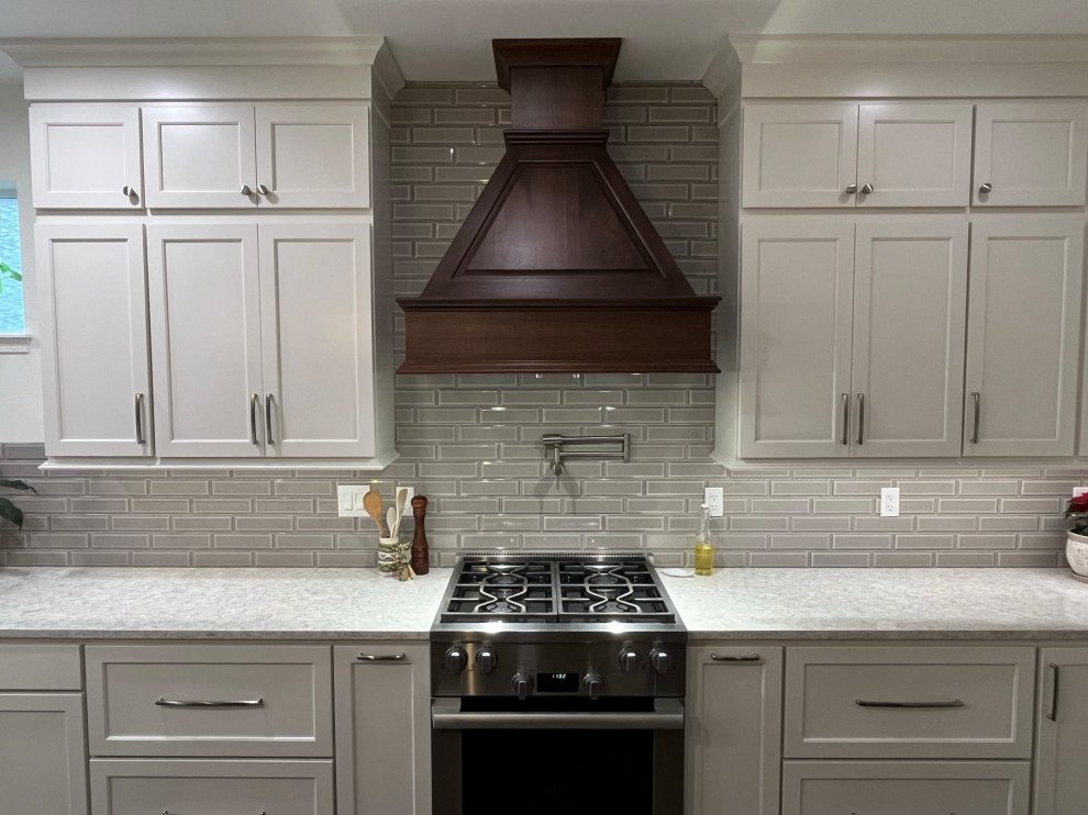 Example of a large transitional l-shaped vinyl floor eat-in kitchen design in Seattle with an undermount sink, recessed-panel cabinets, medium tone wood cabinets, quartz countertops, gray backsplash, porcelain backsplash, stainless steel appliances, an island and white countertops