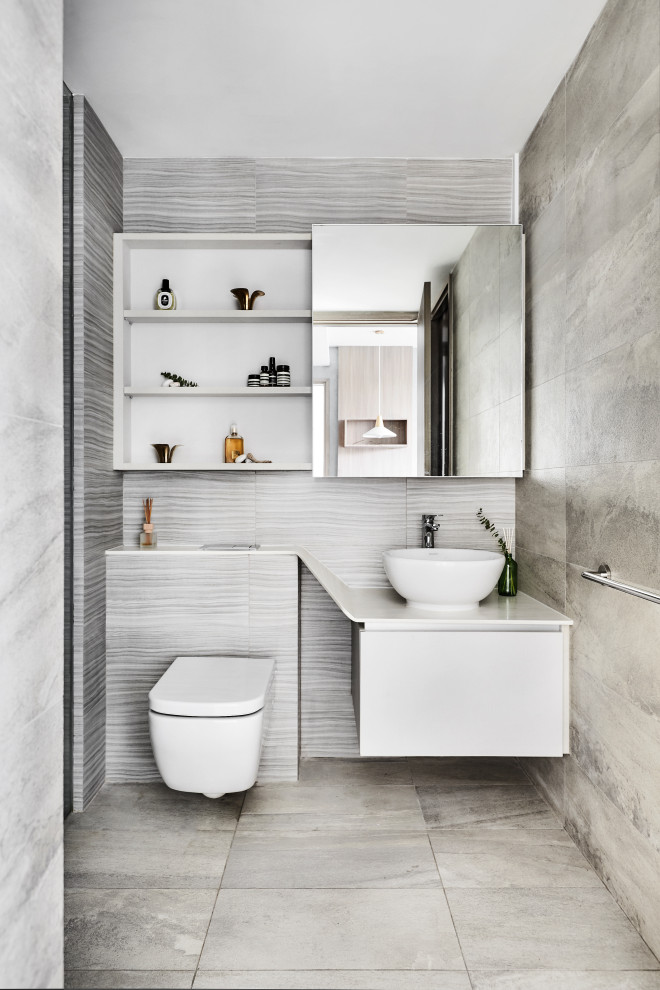 Scandinavian bathroom in Singapore with flat-panel cabinets, white cabinets, a wall-mount toilet, gray tile, a vessel sink, grey floor and white benchtops.