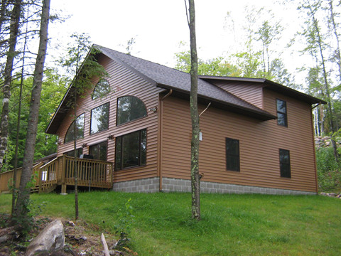 Example of a large mountain style brown two-story vinyl exterior home design with a gambrel roof