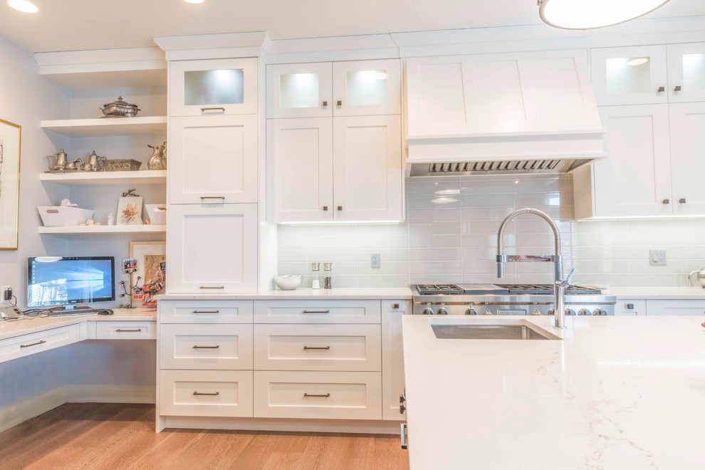 Kitchen - mid-sized transitional u-shaped medium tone wood floor and brown floor kitchen idea in Calgary with an undermount sink, flat-panel cabinets, white cabinets, marble countertops, gray backsplash, ceramic backsplash, paneled appliances and an island