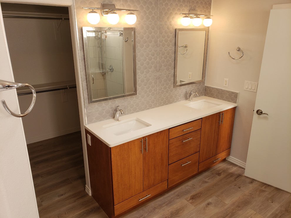 Design ideas for a mid-sized transitional master bathroom in Albuquerque with a corner shower, black walls, medium hardwood floors, an undermount sink, brown floor, a hinged shower door, a freestanding tub, flat-panel cabinets, medium wood cabinets, beige tile, ceramic tile, solid surface benchtops and white benchtops.