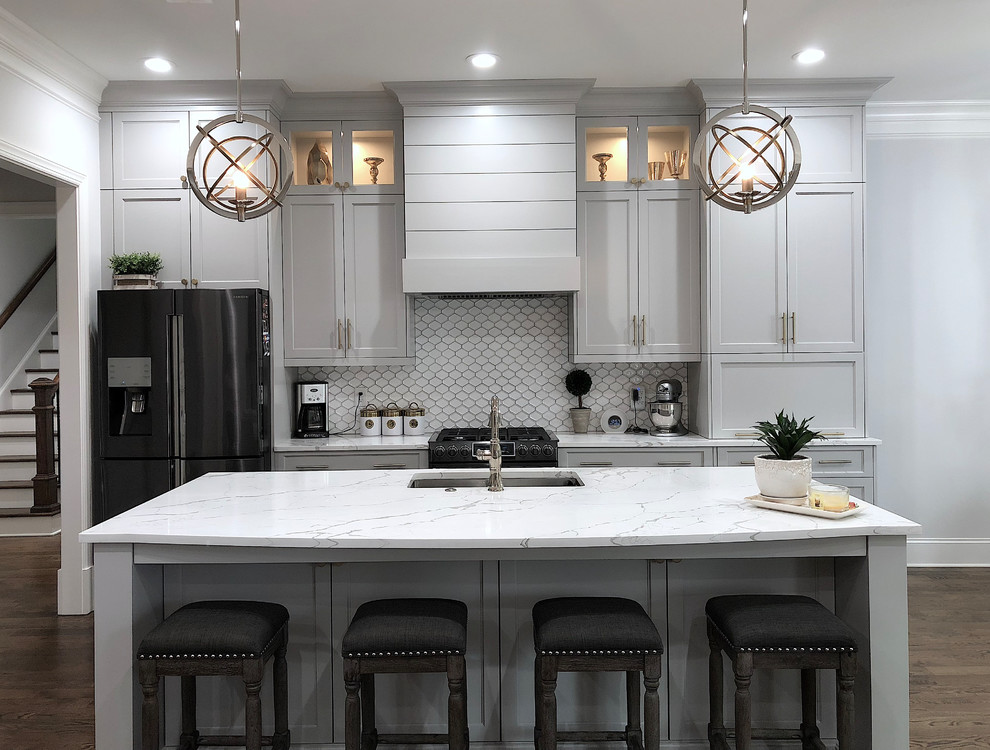 Inspiration for a large transitional u-shaped medium tone wood floor and brown floor eat-in kitchen remodel in Atlanta with an undermount sink, recessed-panel cabinets, white cabinets, quartzite countertops, white backsplash, ceramic backsplash, black appliances, an island and white countertops