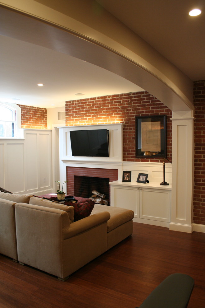Photo of a mid-sized traditional walk-out basement in Providence with white walls, bamboo floors, a standard fireplace and a brick fireplace surround.