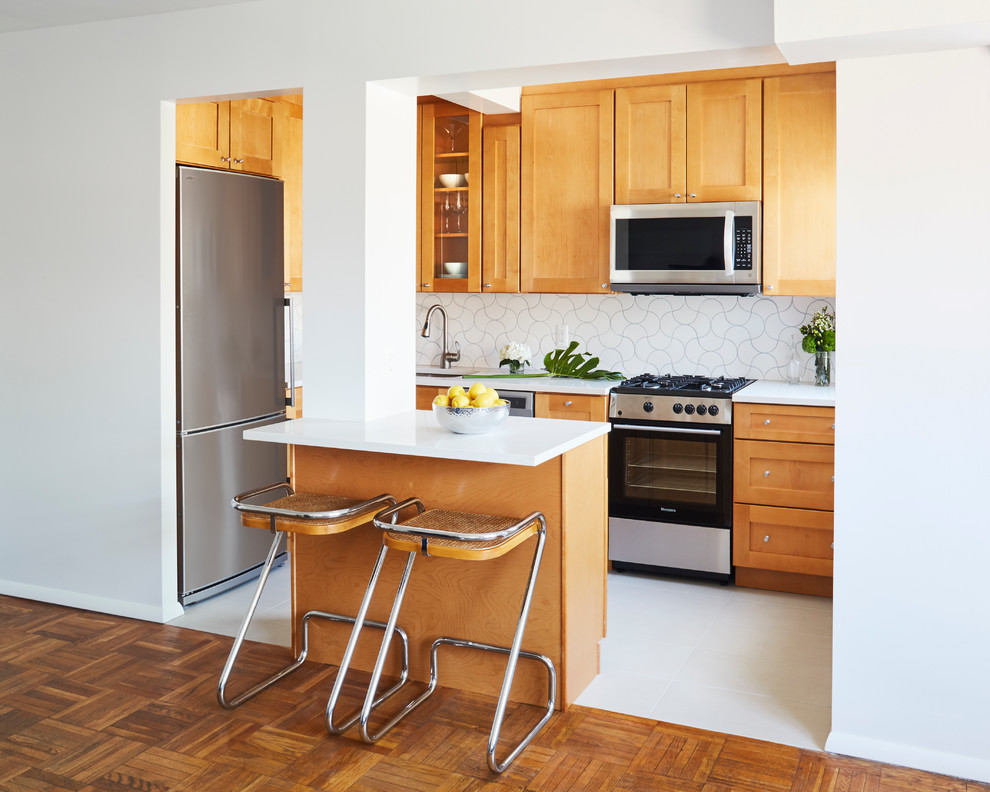 Photo of a small midcentury l-shaped eat-in kitchen in New York with an undermount sink, shaker cabinets, orange cabinets, quartzite benchtops, white splashback, ceramic splashback, stainless steel appliances, porcelain floors and with island.
