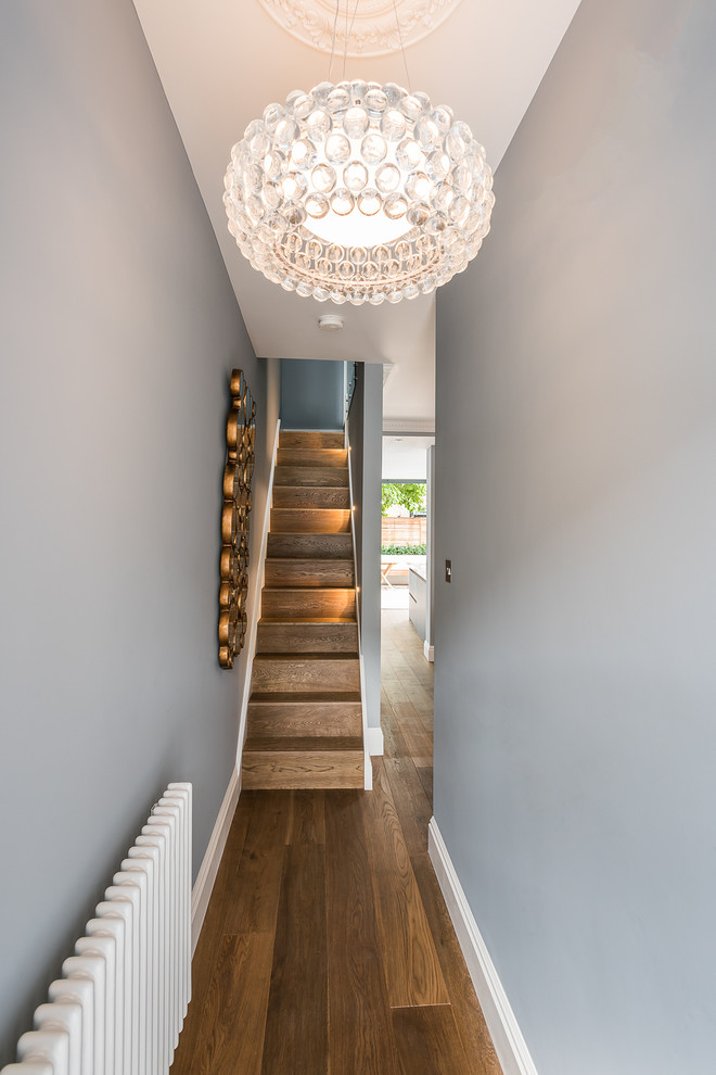 Photo of a small modern hallway in London with blue walls and medium hardwood floors.