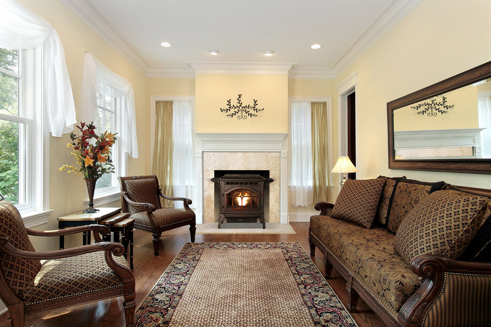 Traditional formal enclosed living room in Other with yellow walls, medium hardwood floors, a wood stove, a metal fireplace surround and brown floor.