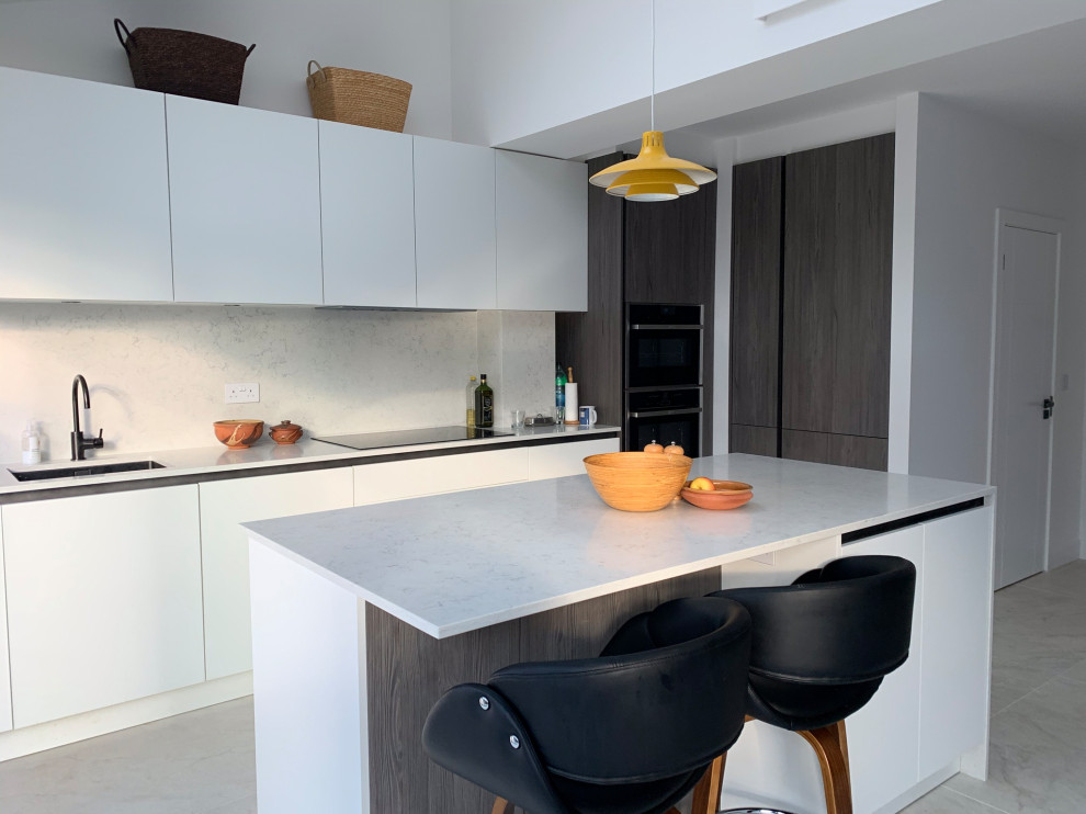 Photo of a mid-sized contemporary l-shaped kitchen in Other with an undermount sink, flat-panel cabinets, white cabinets, beige splashback, panelled appliances, porcelain floors, with island, grey floor and white benchtop.