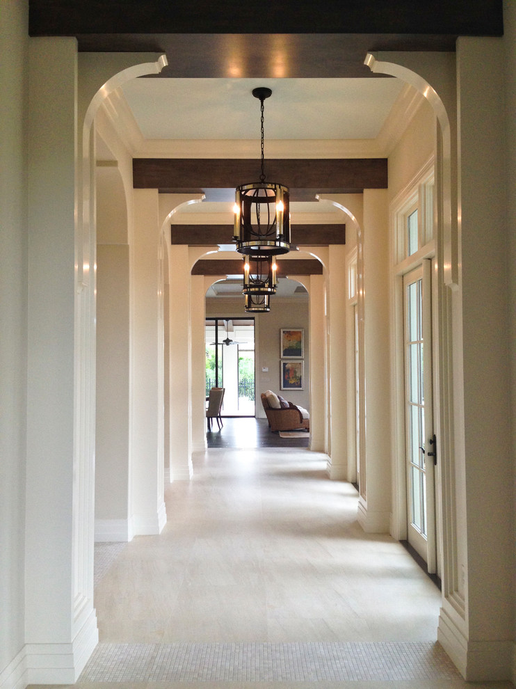 This is an example of a large mediterranean hallway in Tampa with white walls, porcelain floors and beige floor.