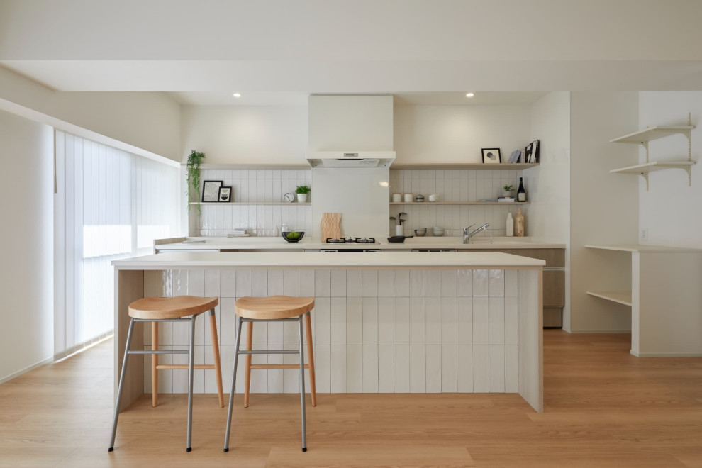 На фото: кухня в стиле модернизм с белым фартуком, белой техникой, бежевым полом и белой столешницей с