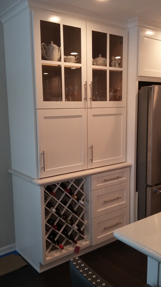 Example of a large transitional l-shaped medium tone wood floor and brown floor open concept kitchen design in Houston with a farmhouse sink, shaker cabinets, white cabinets, quartz countertops, white backsplash, marble backsplash, stainless steel appliances and an island