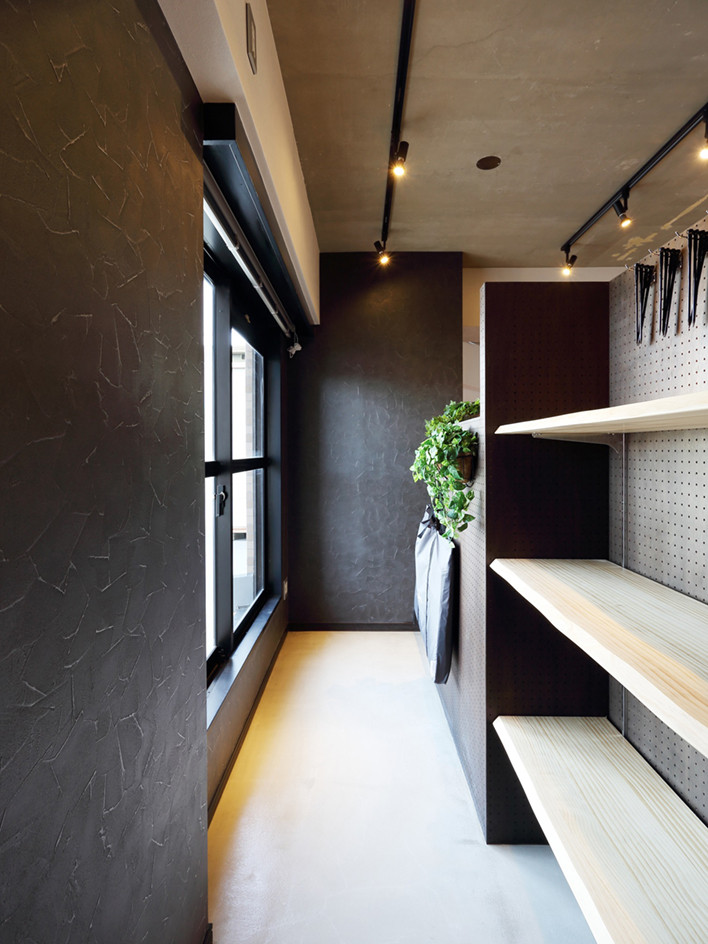 Rustikaler Eingang mit schwarzer Wandfarbe, freigelegten Dachbalken, Tapetenwänden und grauem Boden in Tokio