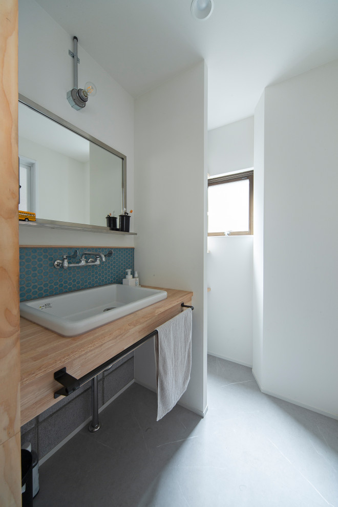 Foto på ett industriellt brun toalett, med öppna hyllor, bruna skåp, blå kakel, mosaik, vita väggar, vinylgolv, ett undermonterad handfat och grått golv