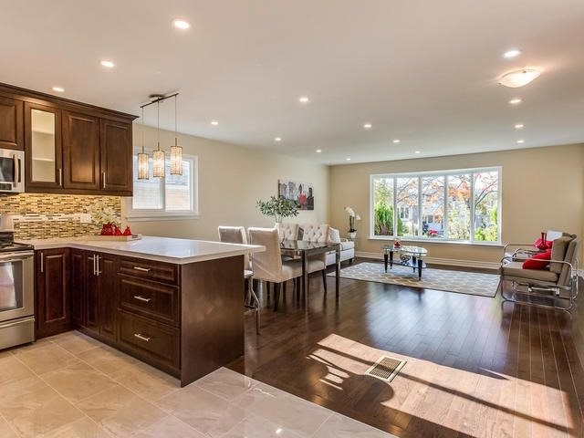 Mid-sized modern l-shaped open plan kitchen in Toronto with a double-bowl sink, raised-panel cabinets, dark wood cabinets, limestone benchtops, multi-coloured splashback, matchstick tile splashback, stainless steel appliances, marble floors, a peninsula and beige floor.